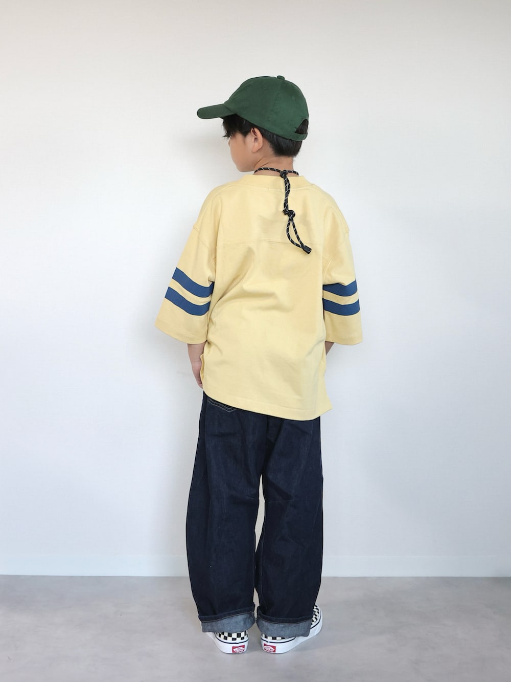 イエロー系のTシャツ/カットソー、ブラック系のスリッポン、ブルー系のパンツを着用したキッズの秋コーディネートの3枚目の写真