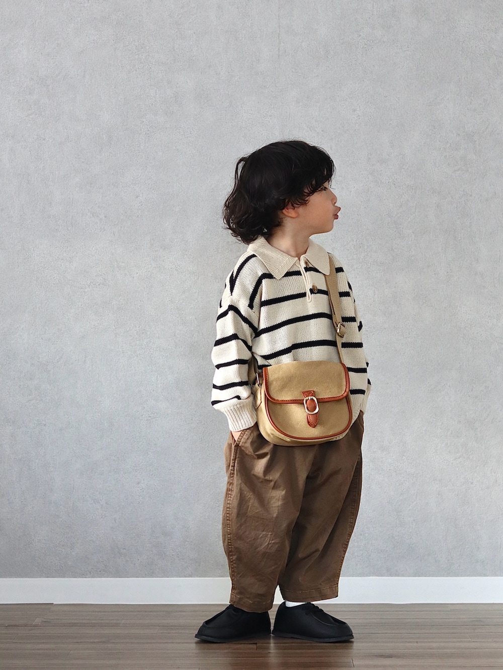 ホワイト系のニット/セーター、ブラウン系のチノパンツ、ブラック系のブーツを着用したキッズの秋コーディネートの2枚目の写真