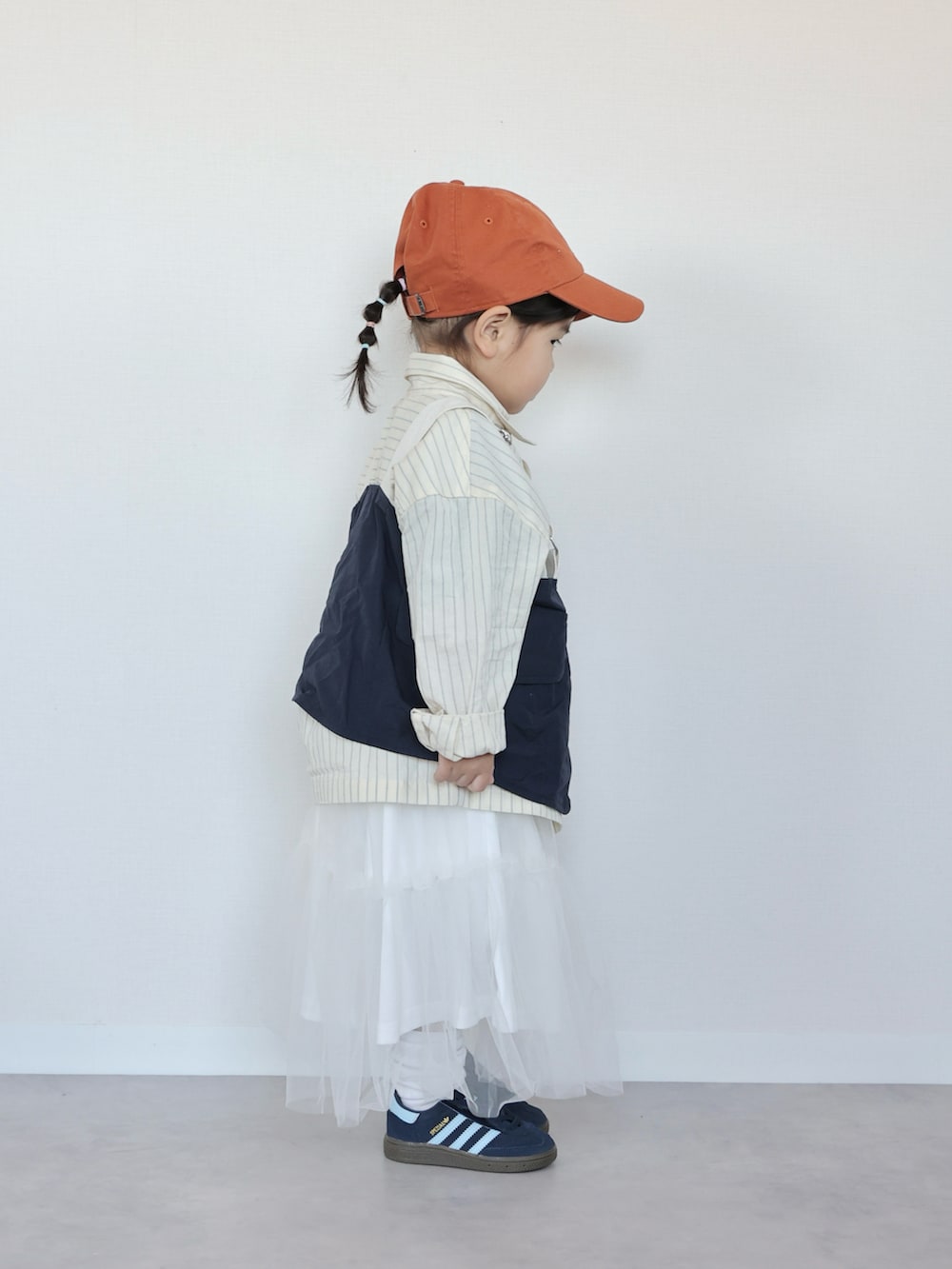 イエロー系のシャツ/ブラウス、ブルー系のベスト、ホワイト系のスカートを着用したキッズの春コーディネートの3枚目の写真