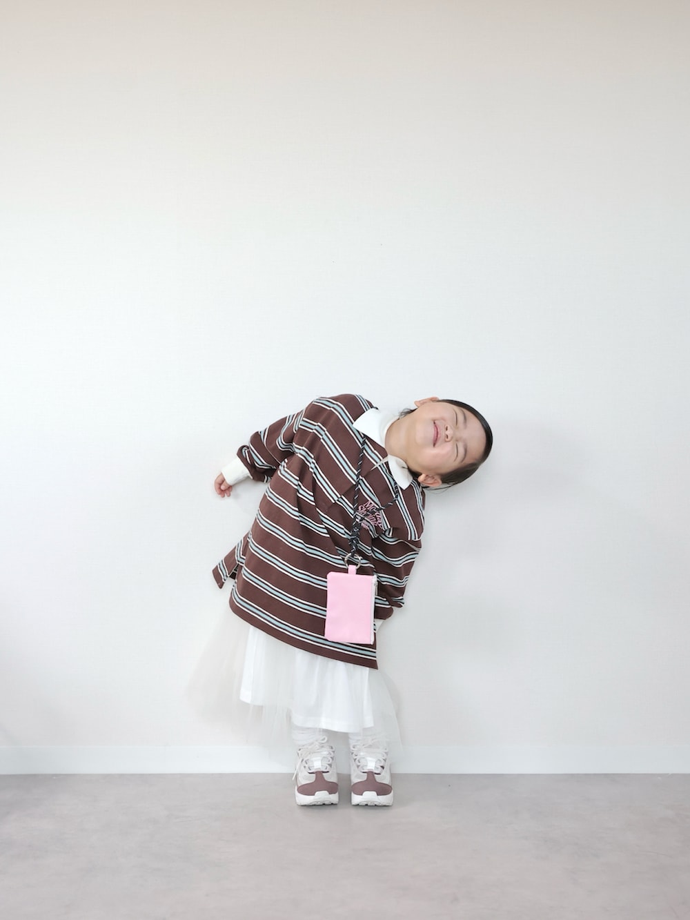 ブラウン系のポロシャツ、ホワイト系のスニーカー、ホワイト系のスカートを着用したキッズの春コーディネートの5枚目の写真