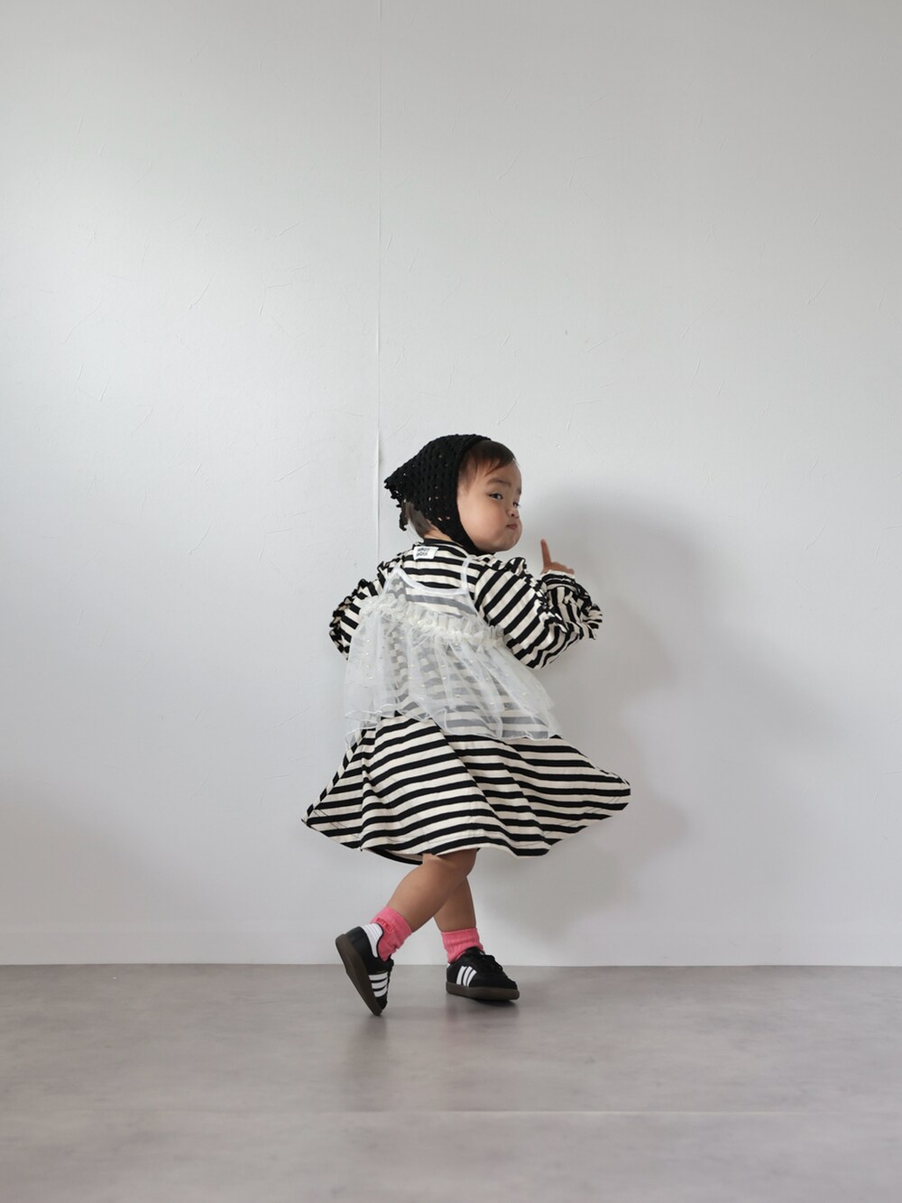 ホワイト系のチュニック、ブラック系のワンピース、ブラック系のスニーカーを着用したキッズの秋コーディネートの5枚目の写真