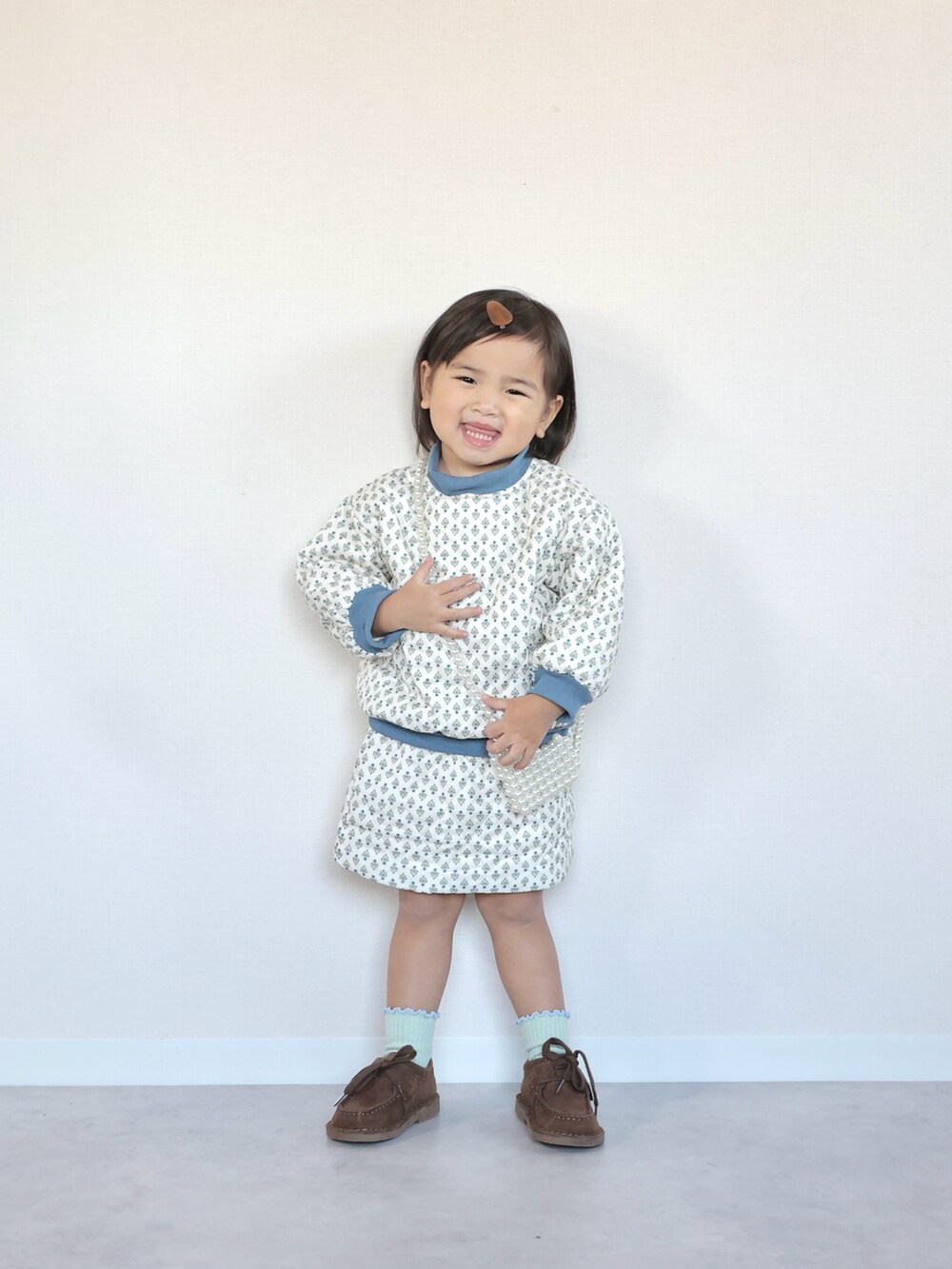 ブラウン系のモカシン/デッキシューズ、ホワイト系のセットアップ、グレー系のその他アウターを着用したキッズの秋コーディネートの3枚目の写真