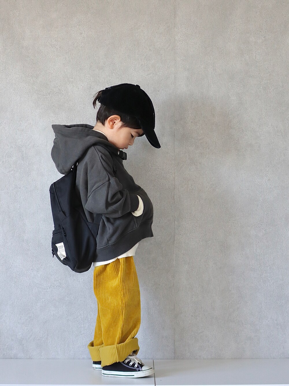 ブラック系のパーカー、ホワイト系のニット/セーター、イエロー系のその他パンツを着用したキッズの冬コーディネートの2枚目の写真