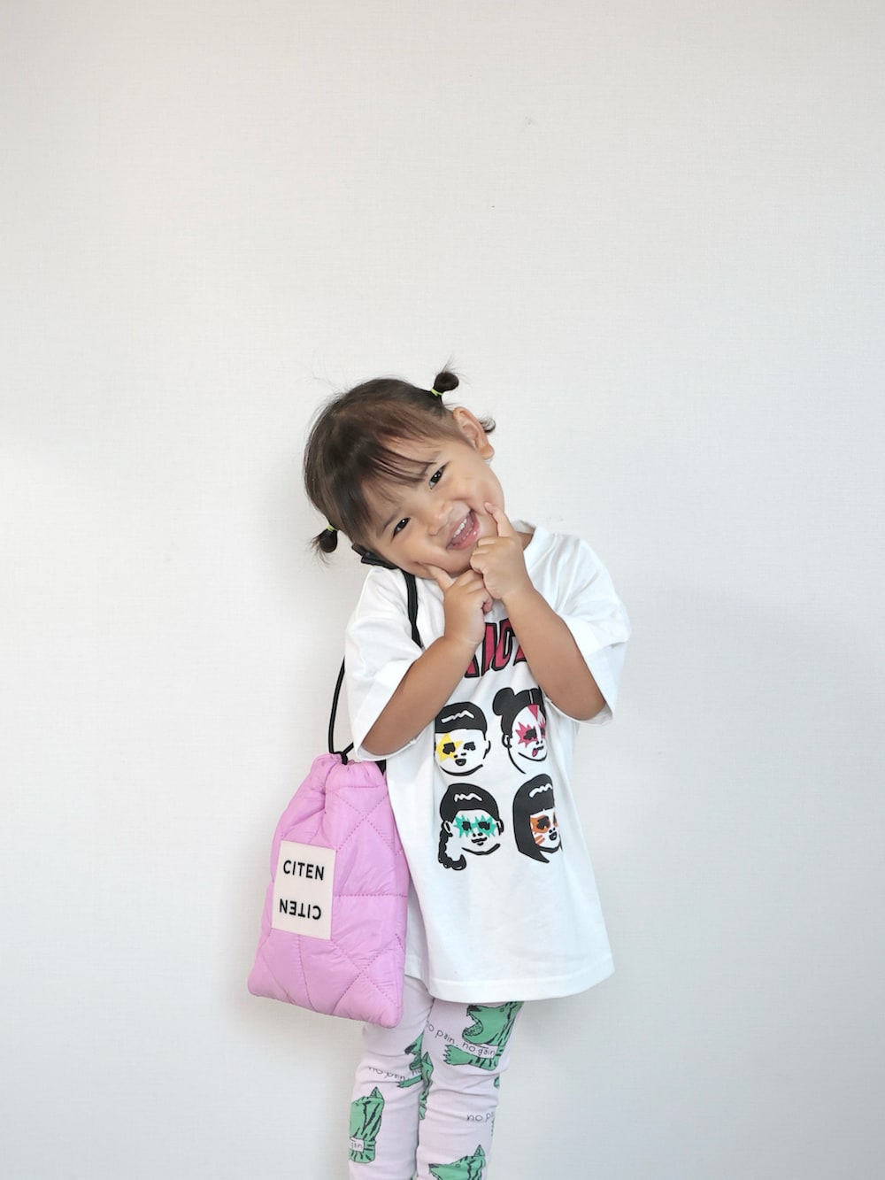 ブラック系のスニーカー、ホワイト系のTシャツ/カットソー、ピンク系のショルダーバッグを着用したキッズの夏コーディネートの2枚目の写真