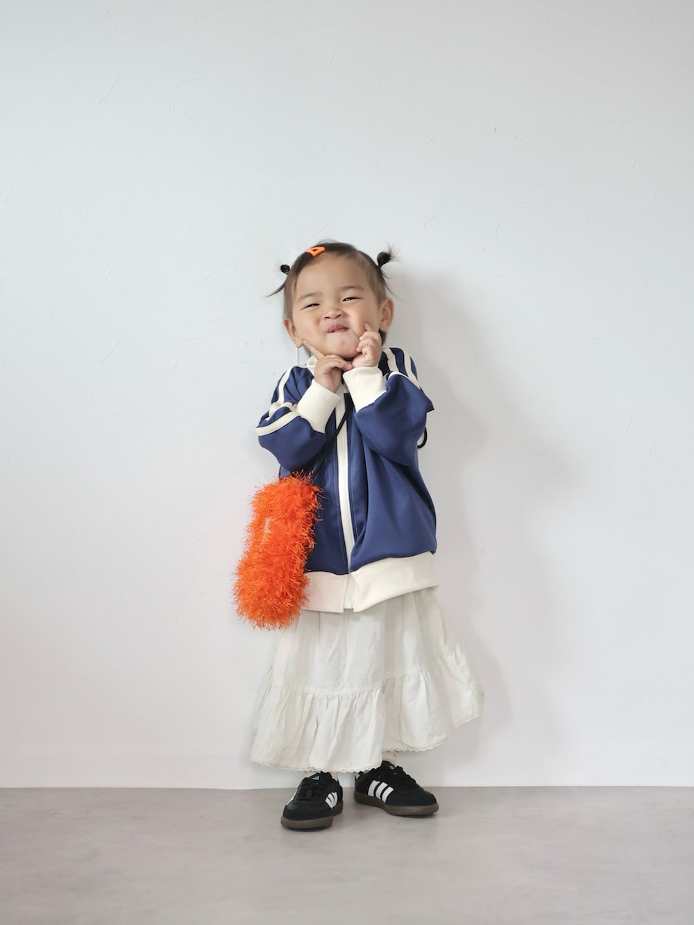 オレンジ系のショルダーバッグ、ブルー系のジャケット/アウター、ホワイト系のスカートを着用したキッズの秋コーディネートの2枚目の写真