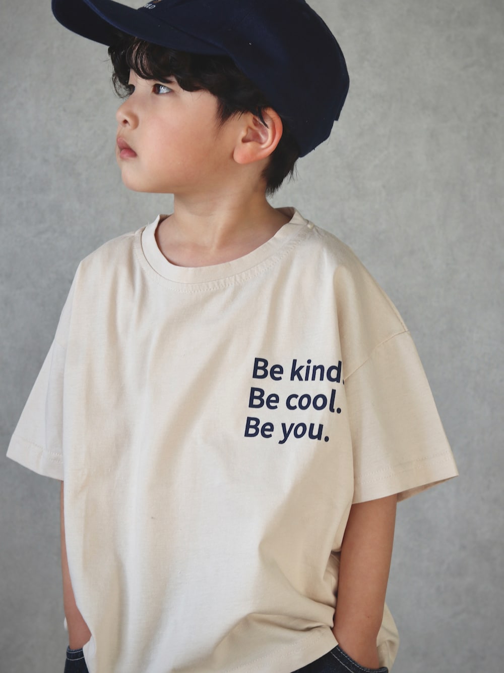 ベージュ系のトップス、ブルー系のデニムパンツ、ベージュ系のサンダルを着用したキッズの春コーディネートの2枚目の写真