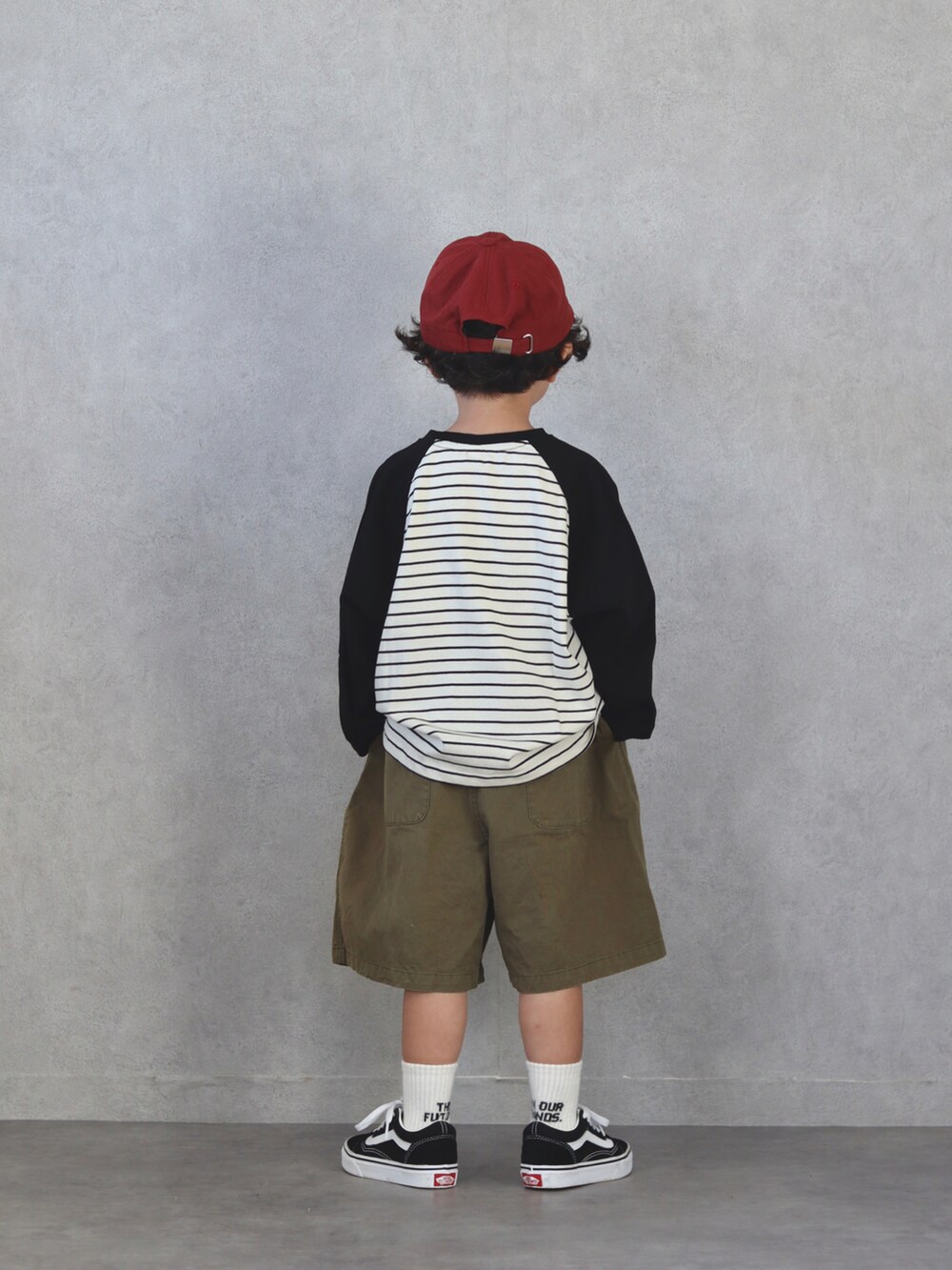 ブラック系のトップス、グリーン系のパンツ、ブラック系のスニーカーを着用したキッズの秋コーディネートの3枚目の写真