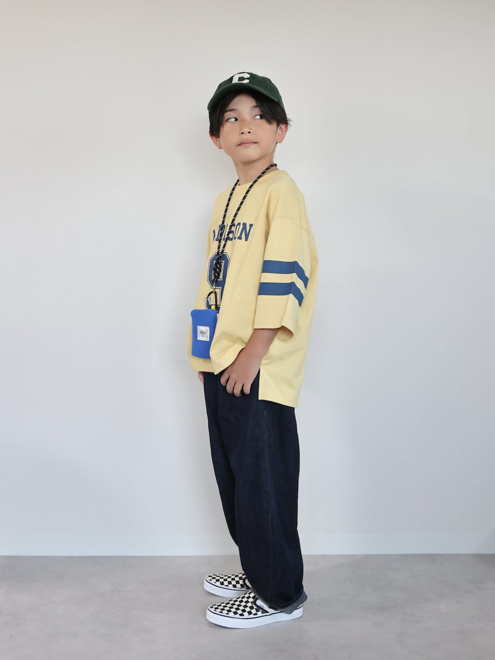 イエロー系のTシャツ/カットソー、ブラック系のスリッポン、ブルー系のパンツを着用したキッズの秋コーディネートの2枚目の写真