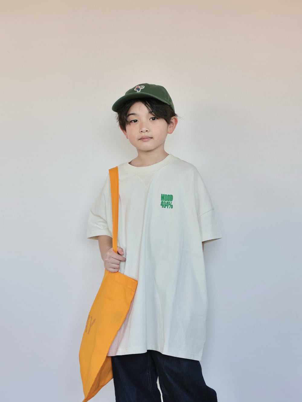 ホワイト系のTシャツ/カットソー、オレンジ系のトートバッグ、ベージュ系のスニーカーを着用したキッズの春コーディネートの2枚目の写真