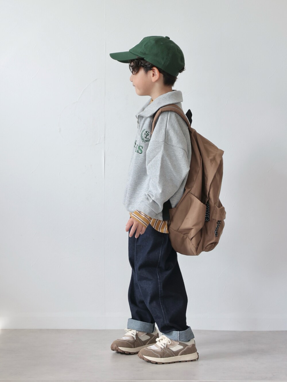 グレー系のスウェット、イエロー系のシャツ/ブラウス、ブルー系のデニムパンツを着用したキッズの秋コーディネートの3枚目の写真