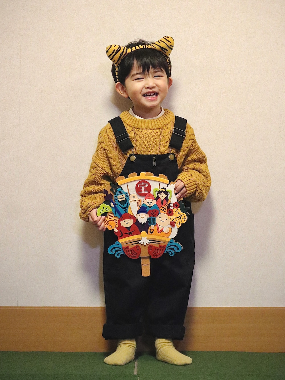 イエロー系のニット/セーター、ホワイト系のシャツ/ブラウス、ブラック系のデニムパンツを着用したキッズの冬コーディネートの3枚目の写真