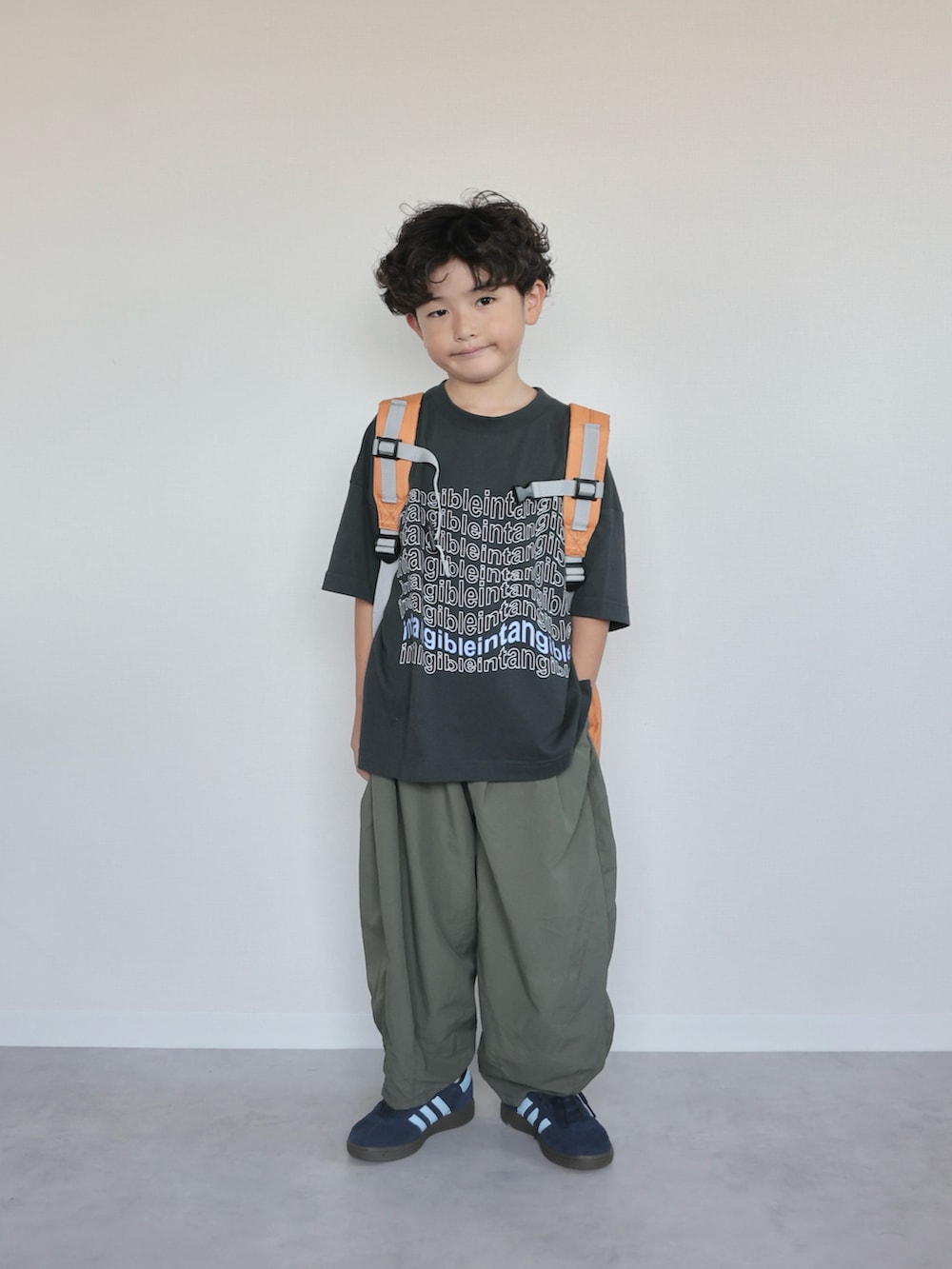 ブラック系のTシャツ/カットソー、グリーン系のその他パンツ、オレンジ系のバックパック/リュックを着用したキッズの夏コーディネートの2枚目の写真