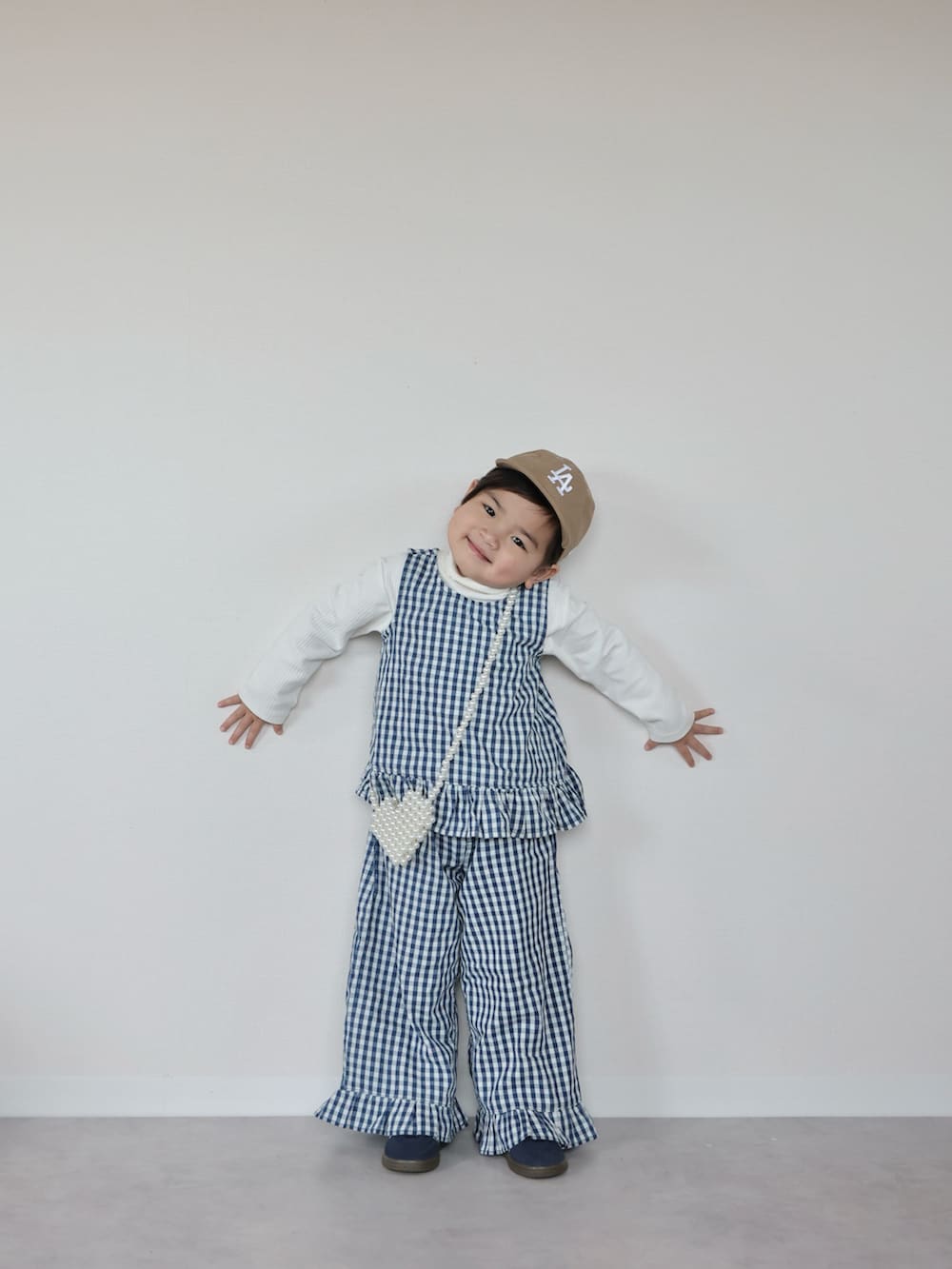 ホワイト系のセットアップ、ブルー系のスニーカー、ホワイト系のショルダーバッグを着用したキッズの春コーディネートの5枚目の写真