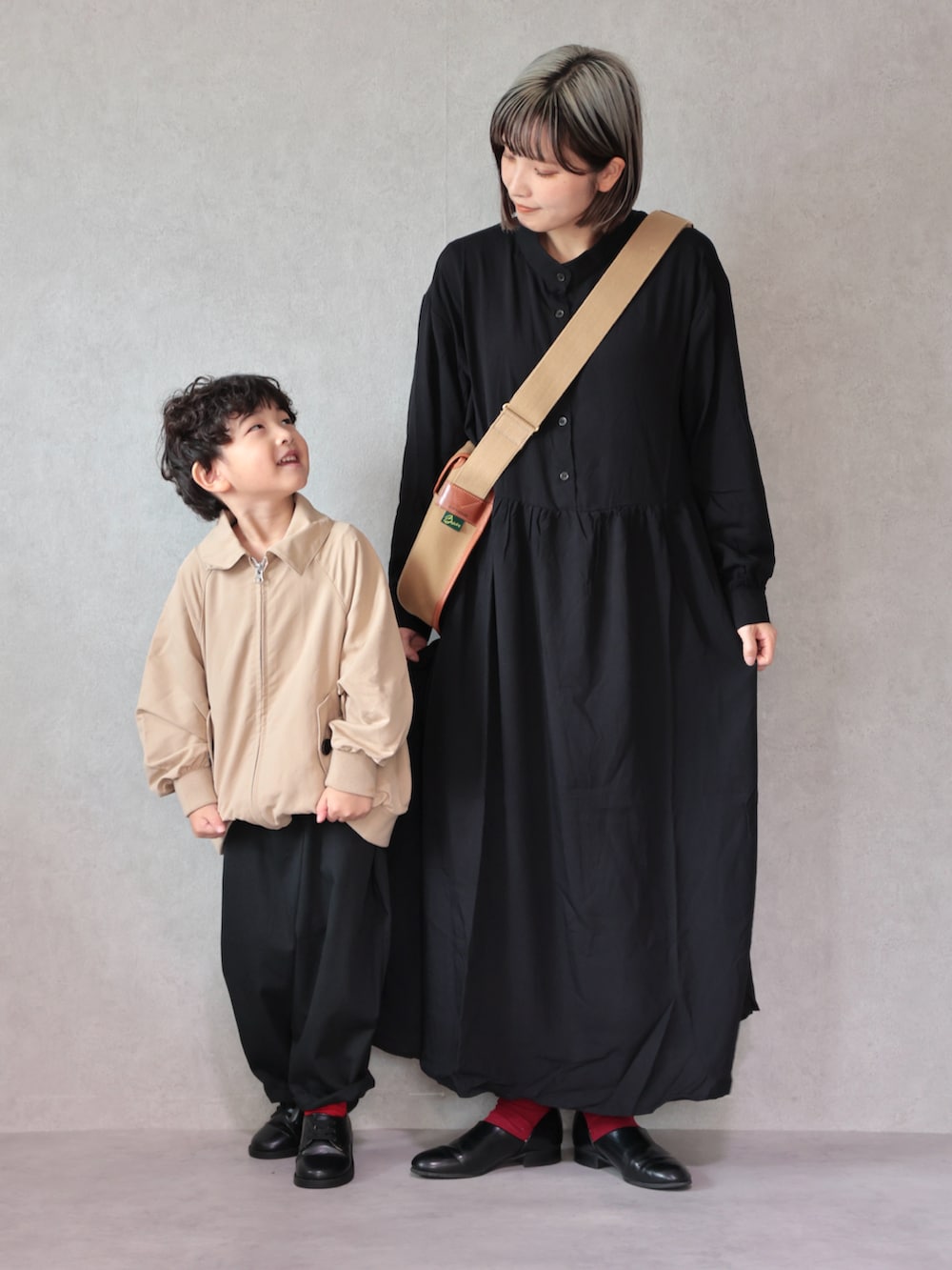 ベージュ系のトレンチコート、ブラック系のワンピース、ブラック系のドレスシューズを着用したキッズの冬コーディネートの2枚目の写真