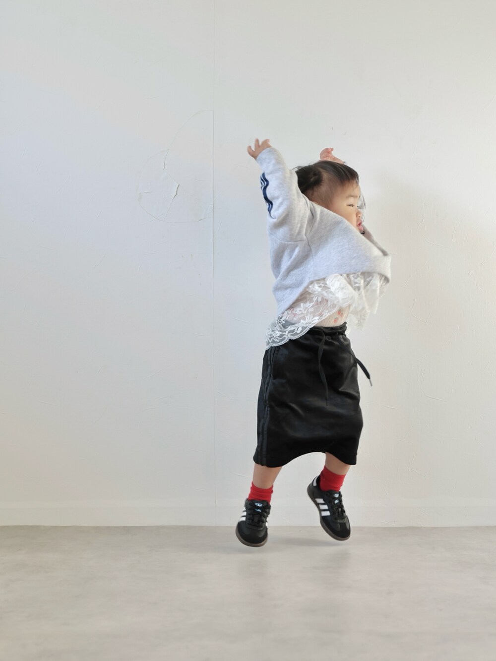 グレー系のスウェット、ブラック系のスカート、ブラック系のスニーカーを着用したキッズの秋コーディネートの3枚目の写真