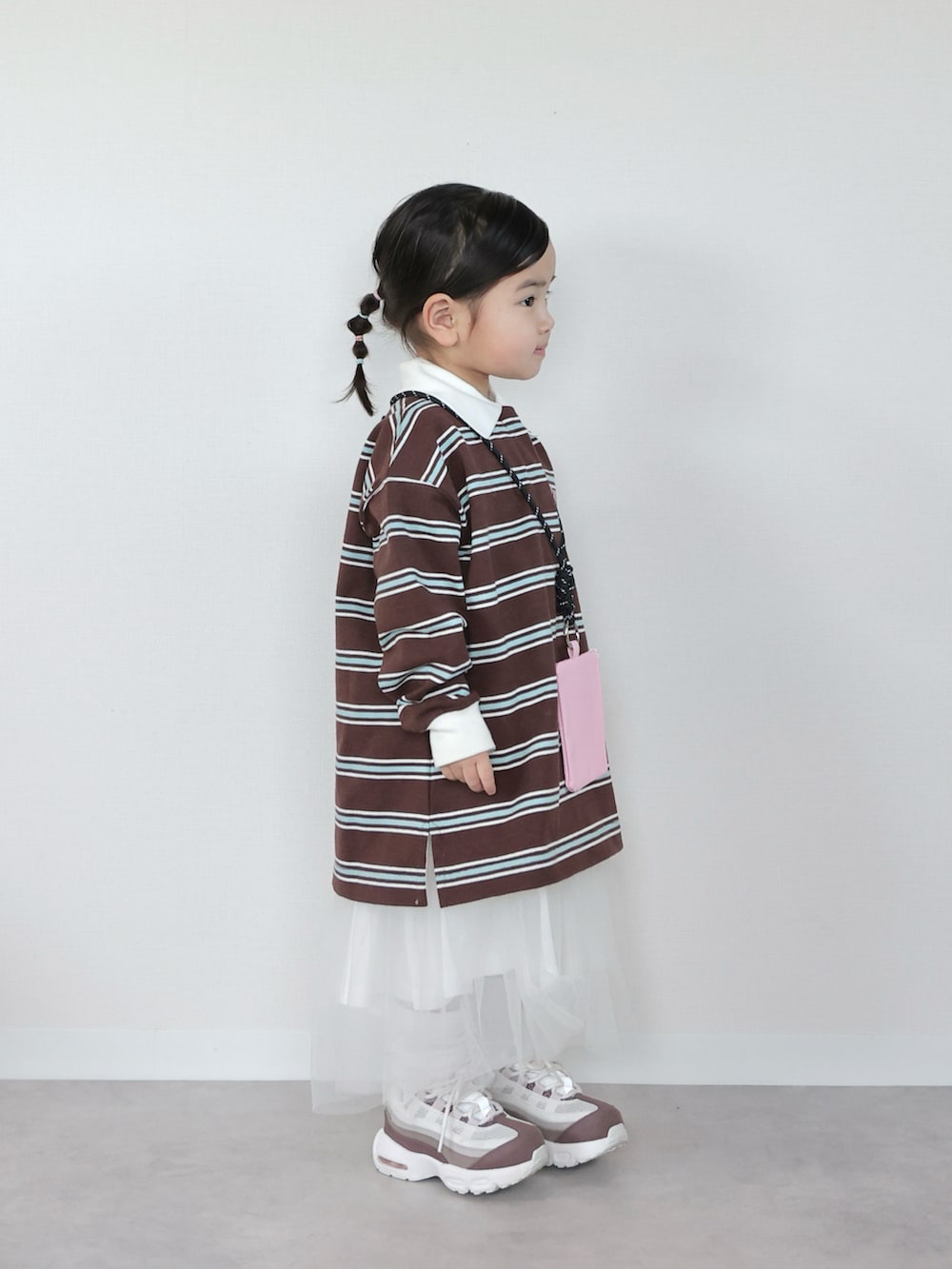 ブラウン系のポロシャツ、ホワイト系のスニーカー、ホワイト系のスカートを着用したキッズの春コーディネートの2枚目の写真