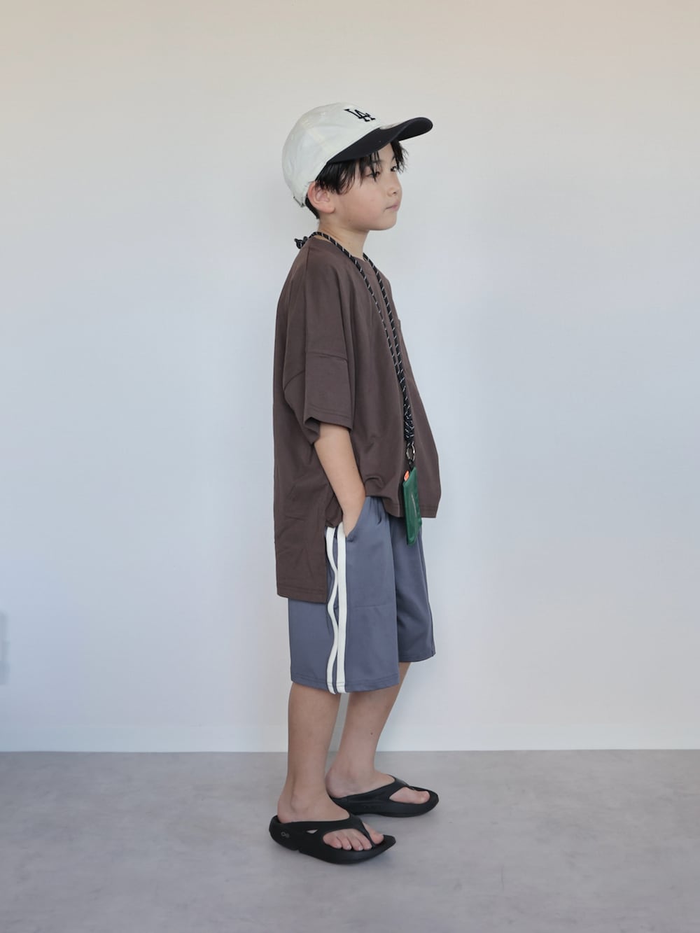 ブラウン系のTシャツ/カットソー、ブラック系のサンダル、グレー系のスウェットパンツを着用したキッズの夏コーディネートの2枚目の写真