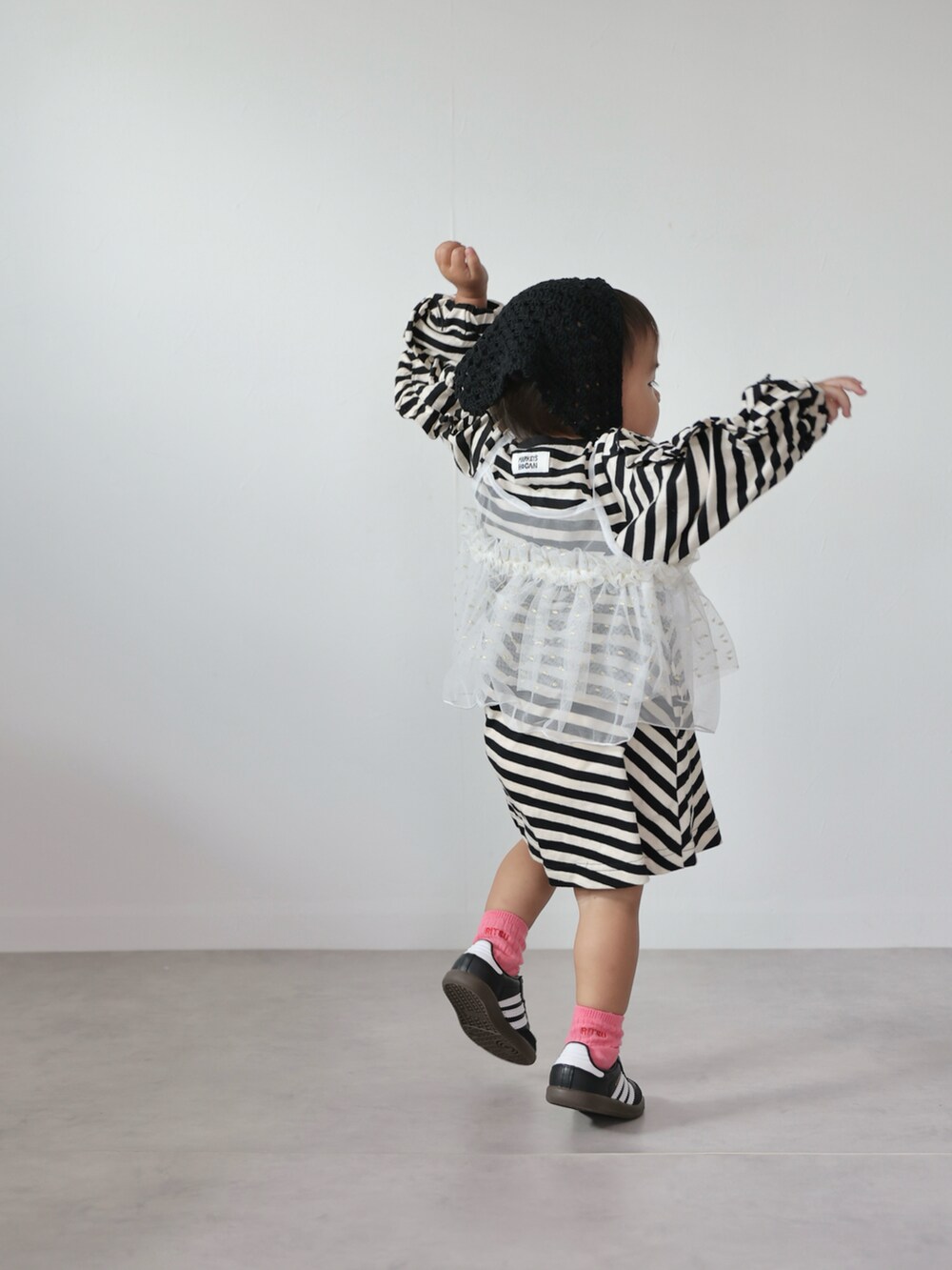 ホワイト系のチュニック、ブラック系のワンピース、ブラック系のスニーカーを着用したキッズの秋コーディネートの3枚目の写真