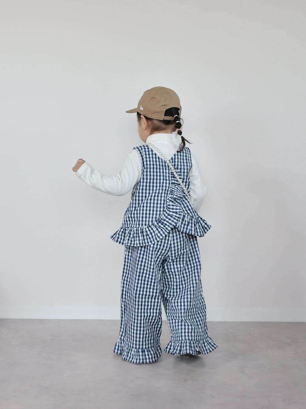 ホワイト系のセットアップ、ブルー系のスニーカー、ホワイト系のショルダーバッグを着用したキッズの春コーディネートの3枚目の写真