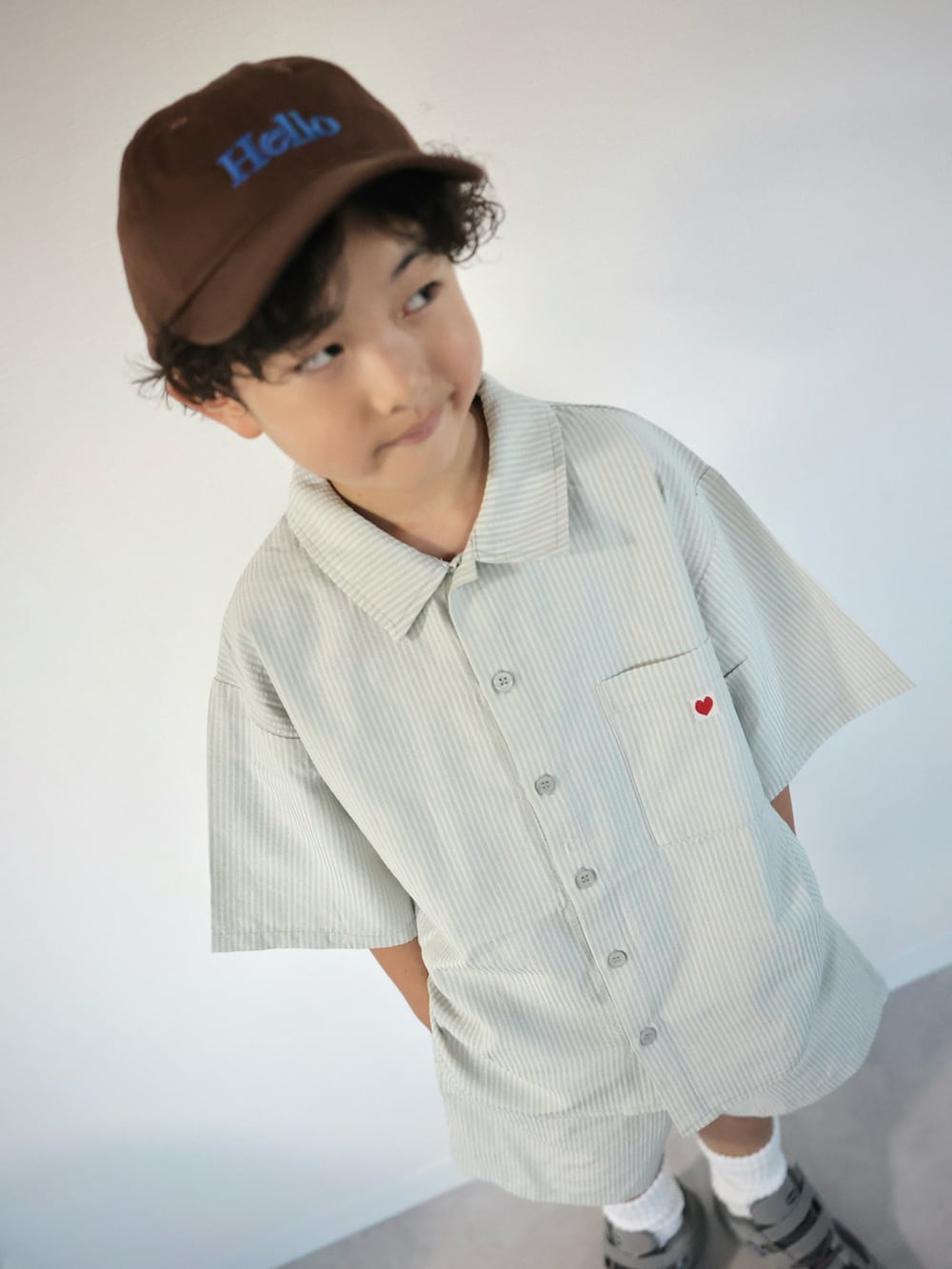 グリーン系のセットアップ、グレー系のスニーカー、ブラウン系のキャップを着用したキッズの夏コーディネートの4枚目の写真