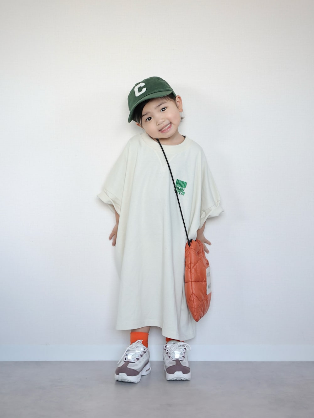 ホワイト系のTシャツ/カットソー、オレンジ系のショルダーバッグ、ホワイト系のスニーカーを着用したキッズの春コーディネートの2枚目の写真