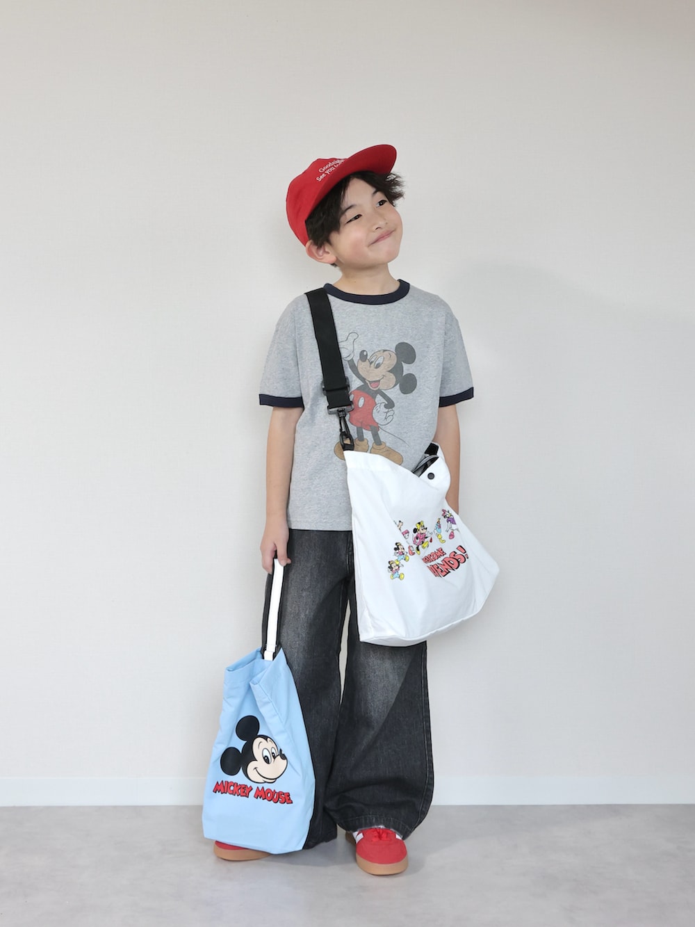 グレー系のTシャツ/カットソー、ブラック系のデニムパンツ、ホワイト系のショルダーバッグを着用したキッズの冬コーディネートの2枚目の写真