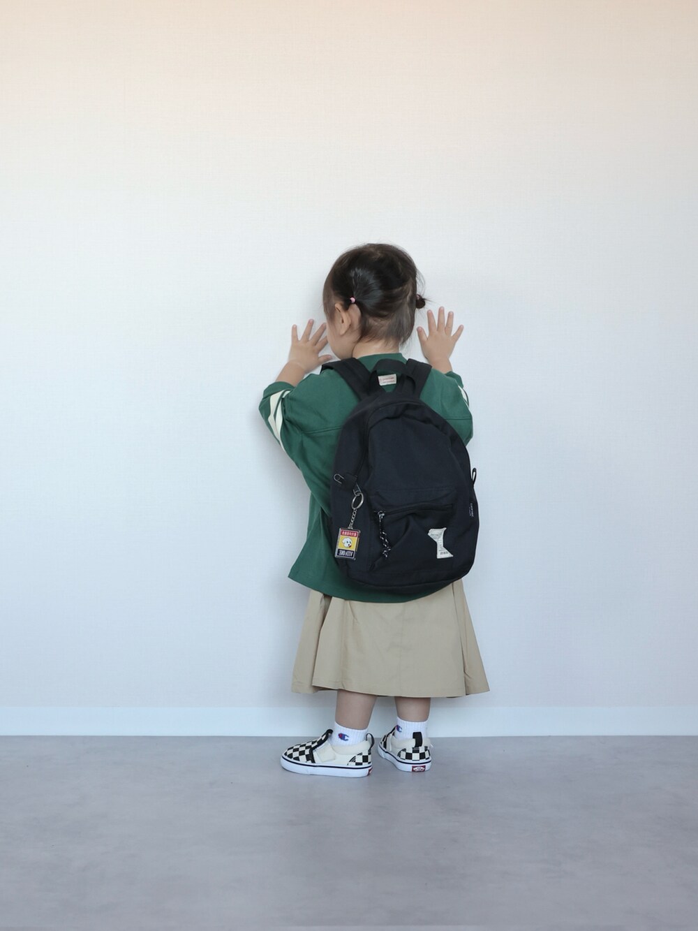 グリーン系のTシャツ/カットソー、ベージュ系のジャンパースカート、ブラック系のスニーカーを着用したキッズの春コーディネートの2枚目の写真