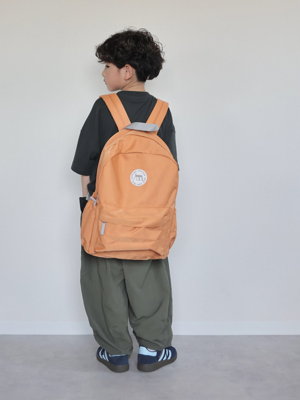 ブラック系のTシャツ/カットソー、グリーン系のその他パンツ、オレンジ系のバックパック/リュックを着用したキッズの夏コーディネートの3枚目の写真