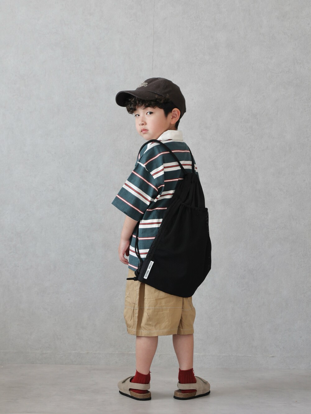 グリーン系のポロシャツ、ベージュ系のその他パンツ、ベージュ系のサンダルを着用したキッズの春コーディネートの3枚目の写真