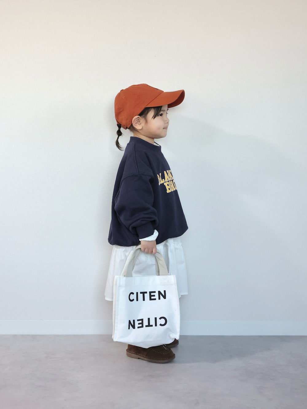 ブラウン系のモカシン/デッキシューズ、ブルー系のスウェット、ホワイト系のワンピースを着用したキッズの冬コーディネートの2枚目の写真