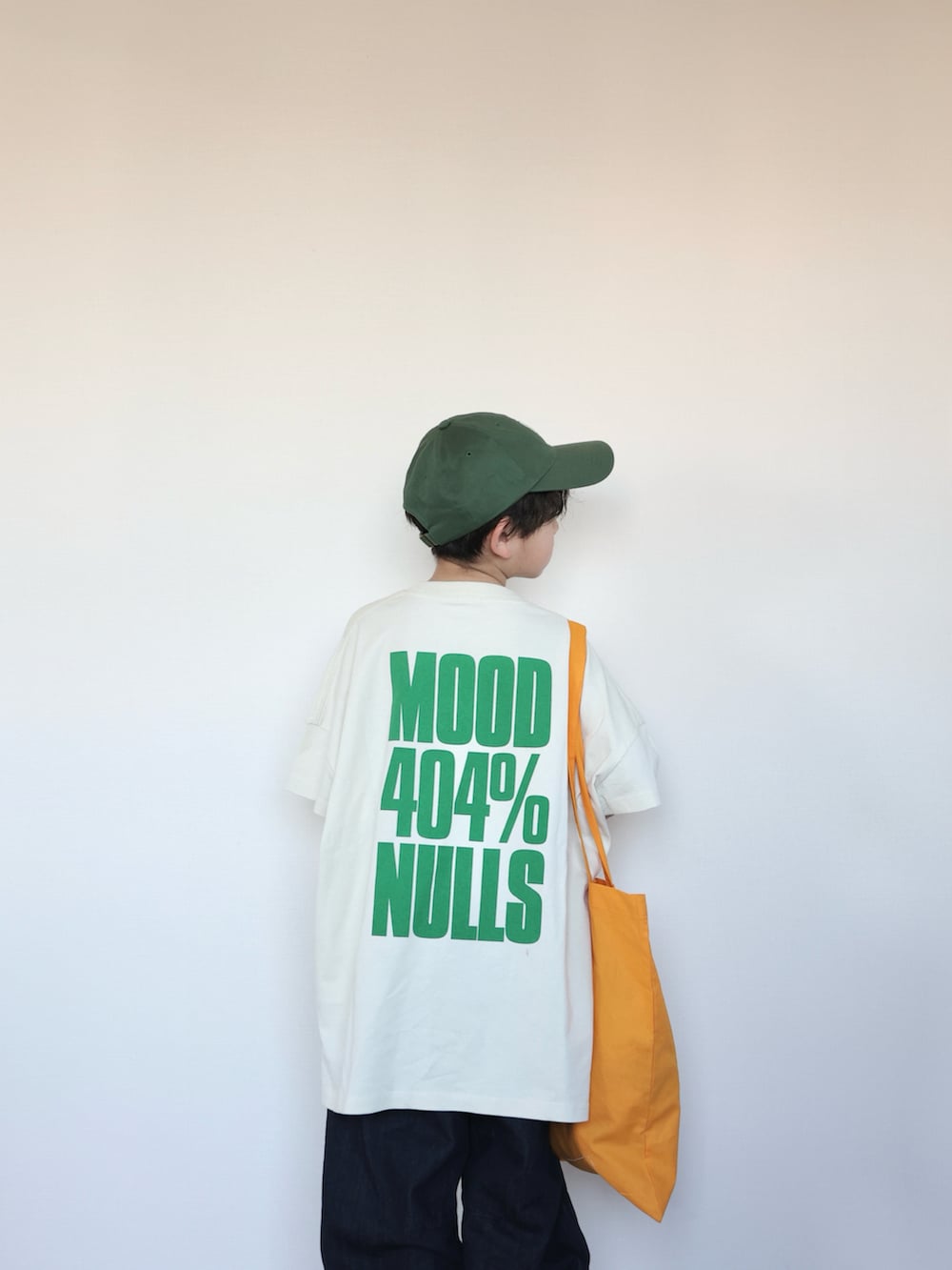 ホワイト系のTシャツ/カットソー、オレンジ系のトートバッグ、ベージュ系のスニーカーを着用したキッズの春コーディネートの3枚目の写真