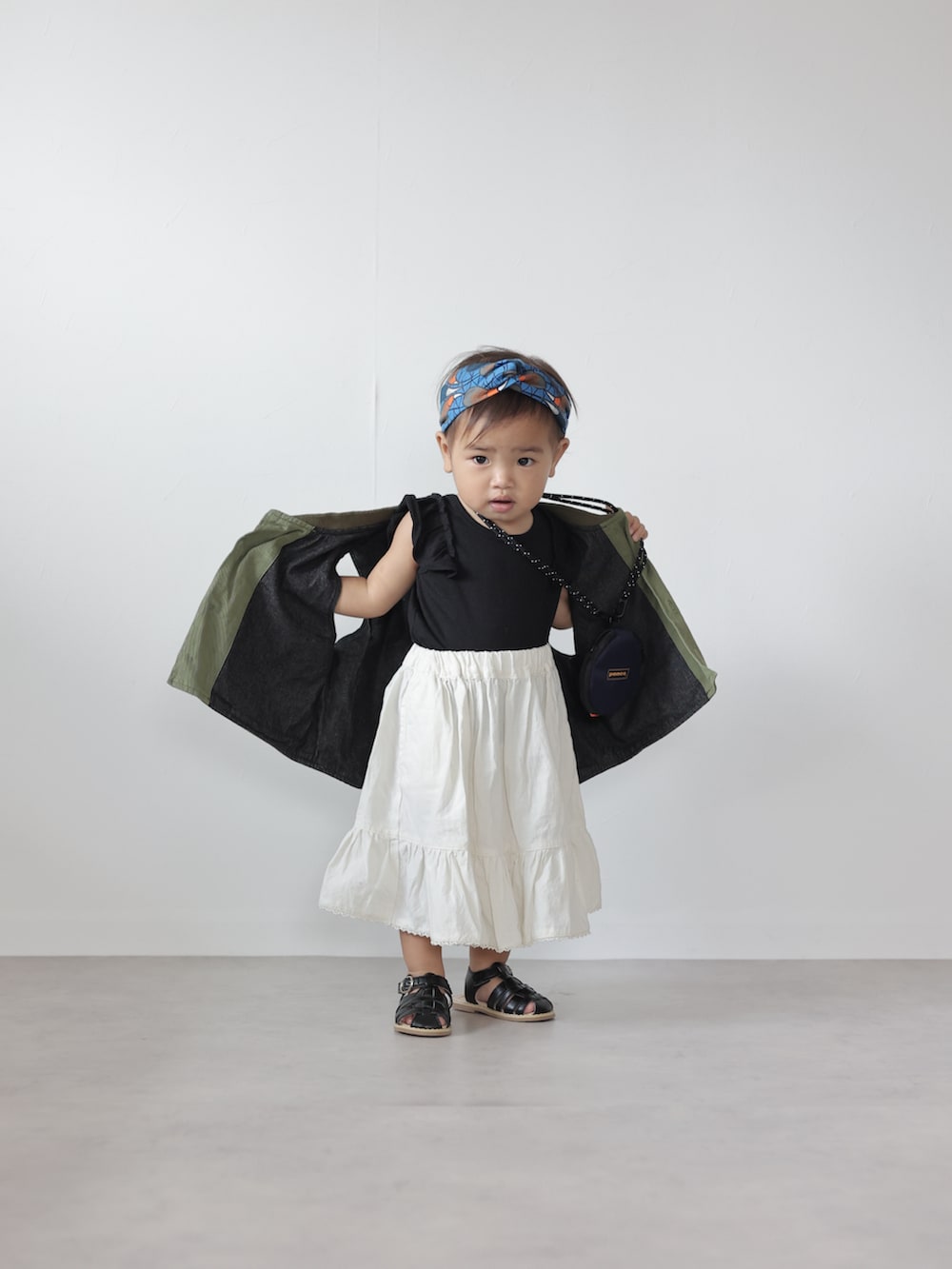 グリーン系のベスト、ブラック系のTシャツ/カットソー、ホワイト系のスカートを着用したキッズの夏コーディネートの4枚目の写真