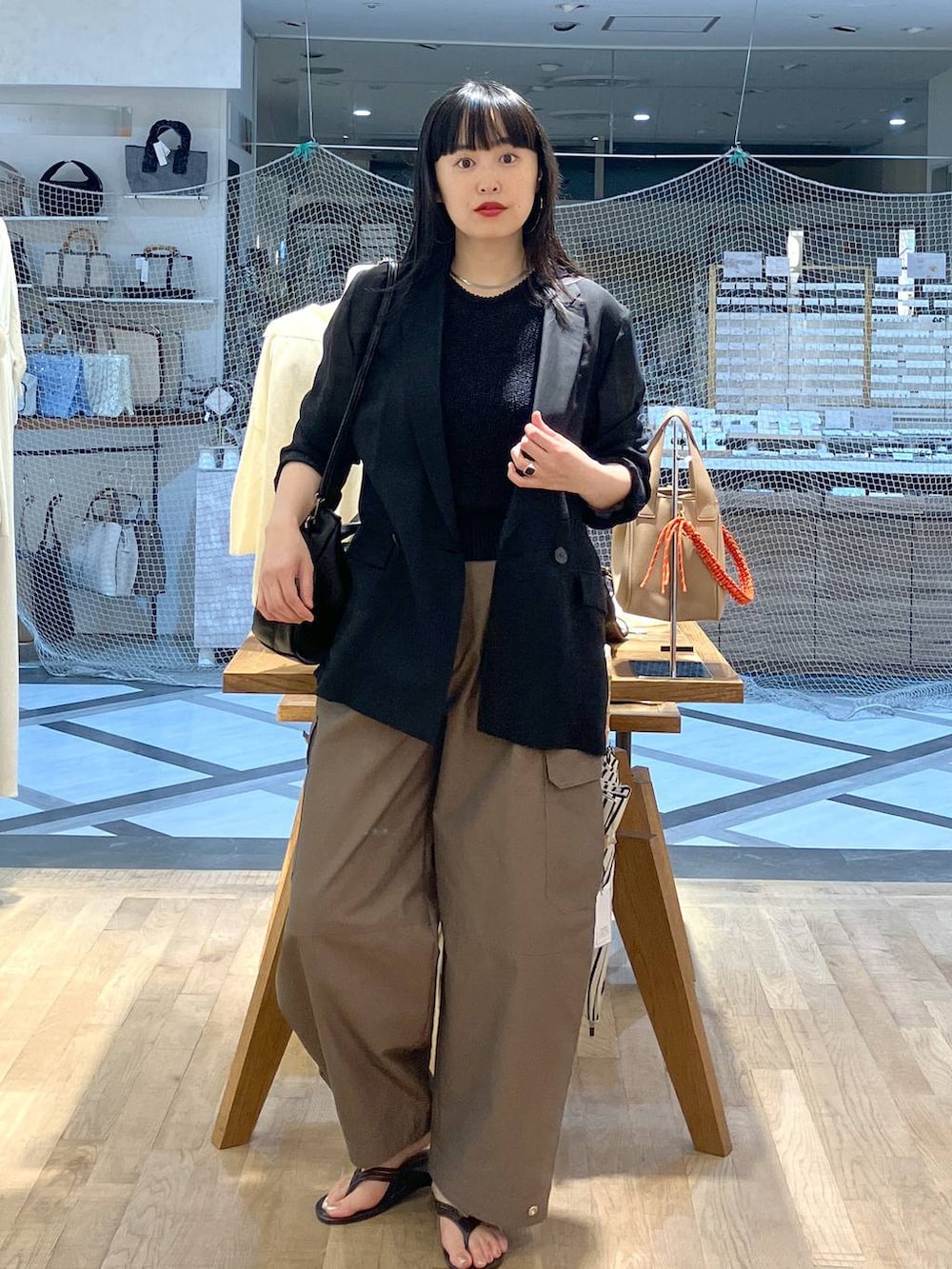 ブラック系のハンドバッグ、ブラック系のテーラードジャケット、ブラック系のキャミソールを着用したレディースの夏コーディネートの4枚目の写真