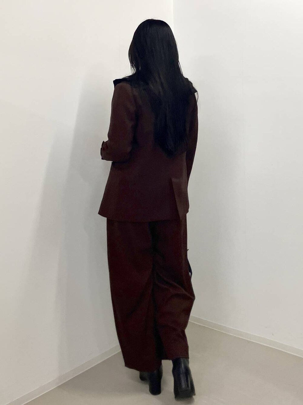 ブラック系のブーツ、ブラウン系のテーラードジャケット、ブラウン系のスラックスを着用したレディースの秋コーディネートの3枚目の写真