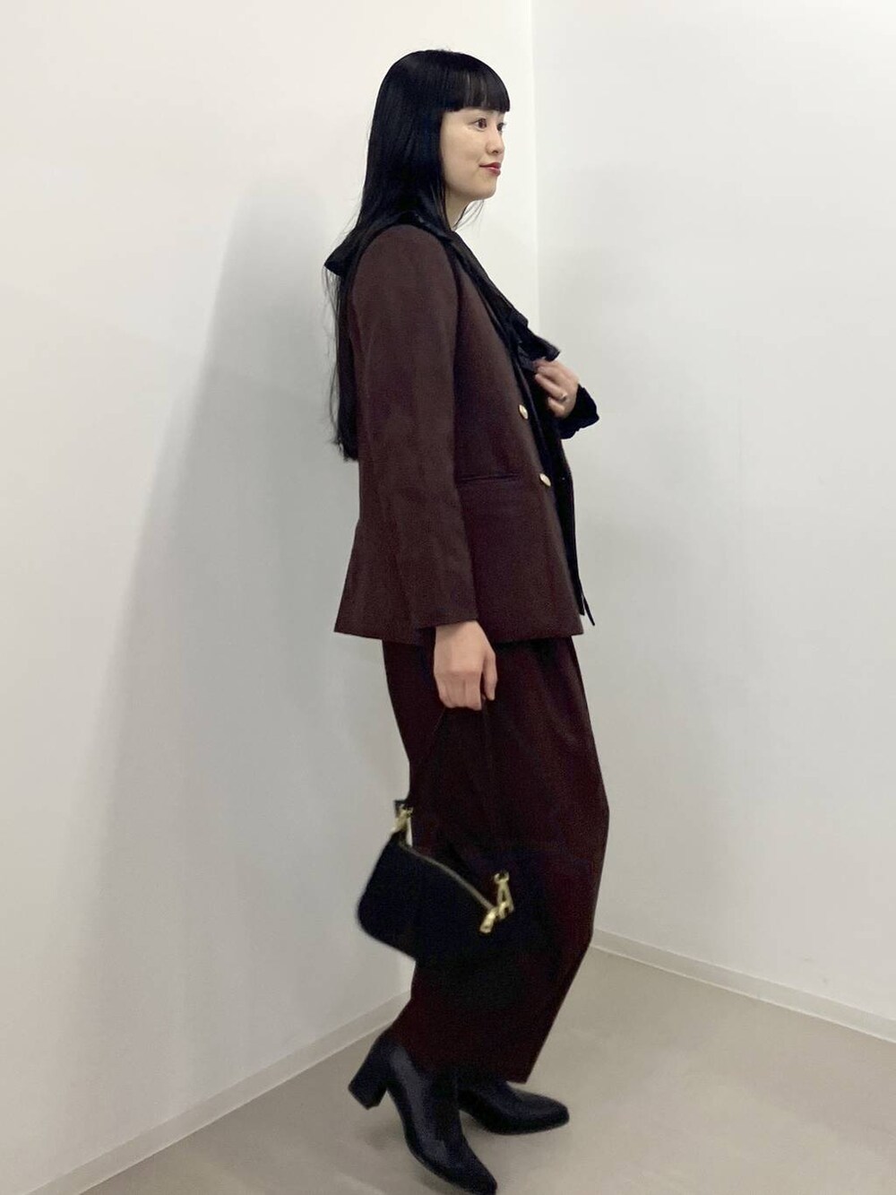 ブラック系のブーツ、ブラウン系のテーラードジャケット、ブラウン系のスラックスを着用したレディースの秋コーディネートの2枚目の写真