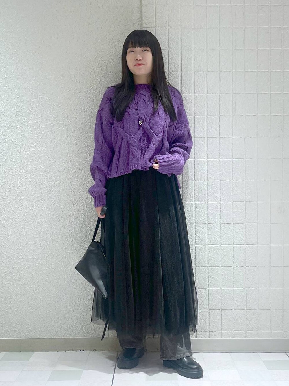 パープル系のニット/セーター、ブラック系のショルダーバッグ、ブラック系のスカートを着用したレディースの冬コーディネートの3枚目の写真