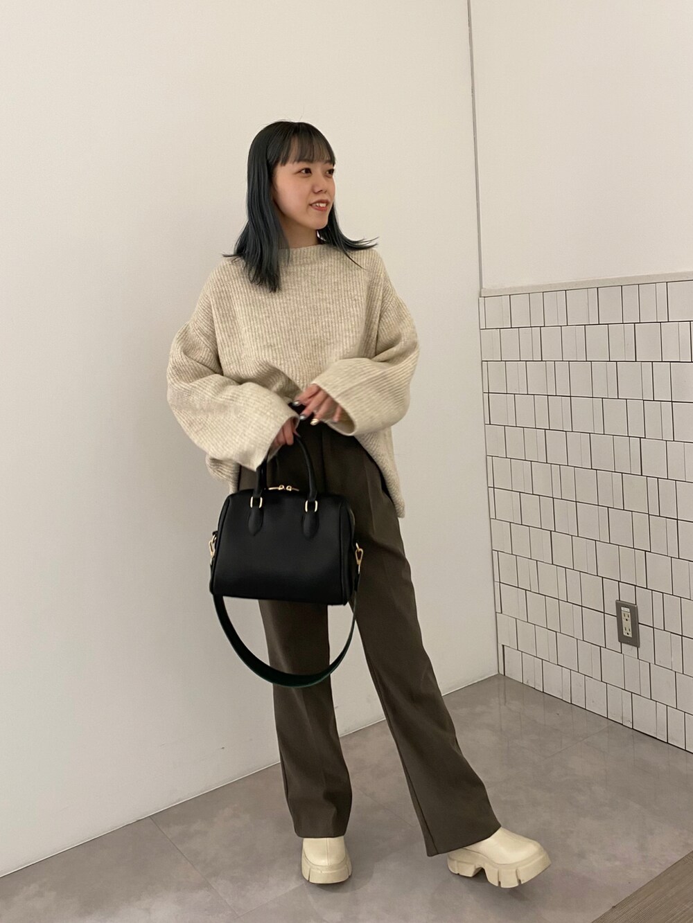 ブラック系のボストンバッグ、ホワイト系のニット/セーター、ブラウン系のその他パンツを着用したレディースの秋コーディネートの2枚目の写真