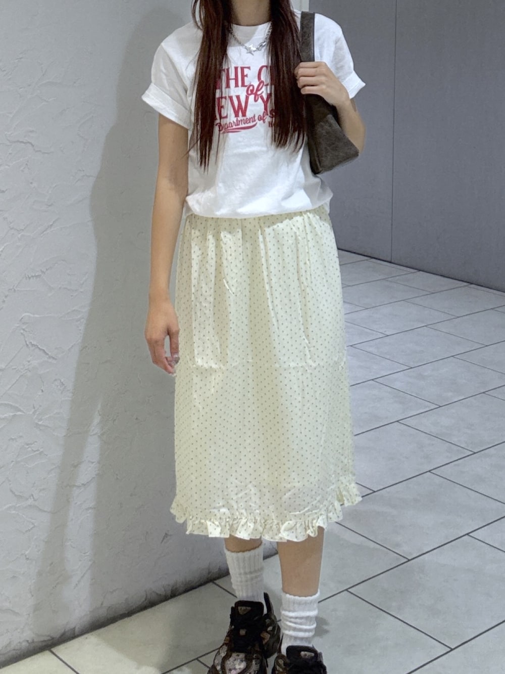 ホワイト系のスカート、ブラウン系のショルダーバッグ、ベージュ系のキャップを着用したレディースの夏コーディネートの2枚目の写真
