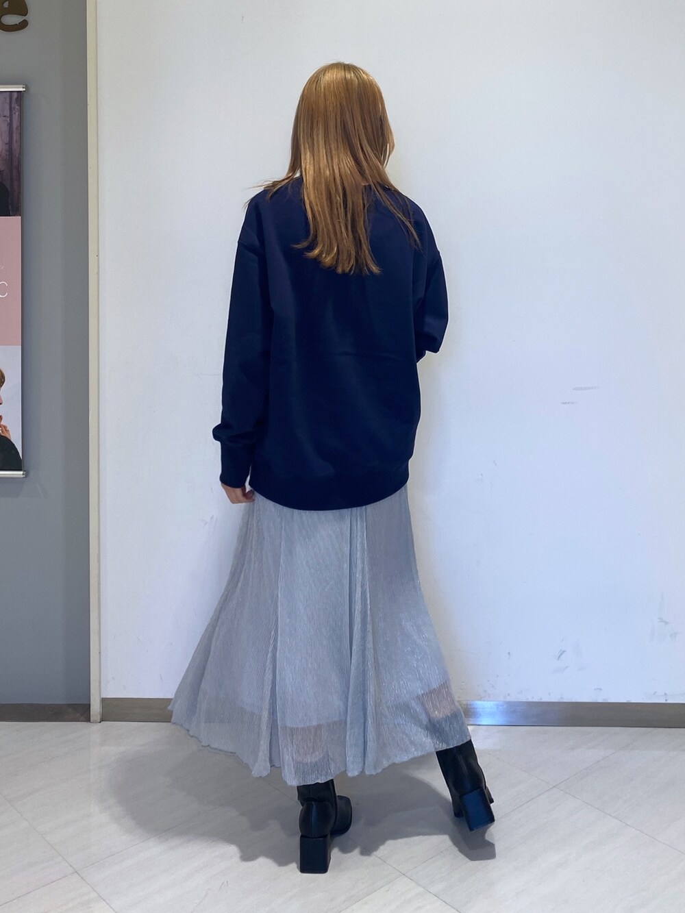 シルバー系のスカート、ブルー系のスウェット、ブラック系のブーツを着用したレディースの冬コーディネートの2枚目の写真