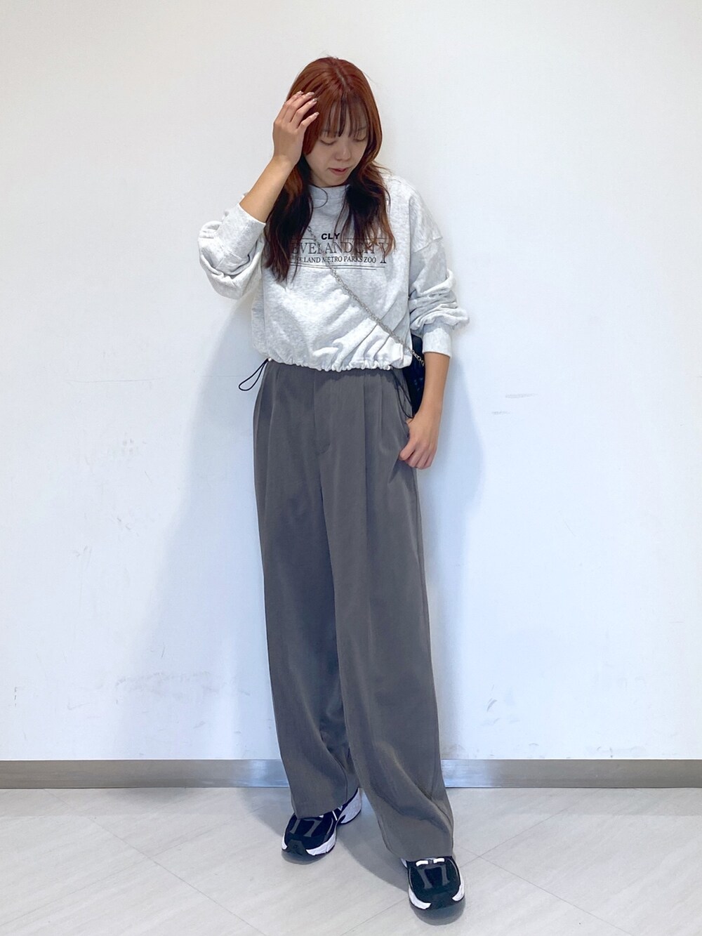 グレー系のスラックス、ホワイト系のTシャツ/カットソー、ブラック系のスニーカーを着用したレディースの秋コーディネートの3枚目の写真