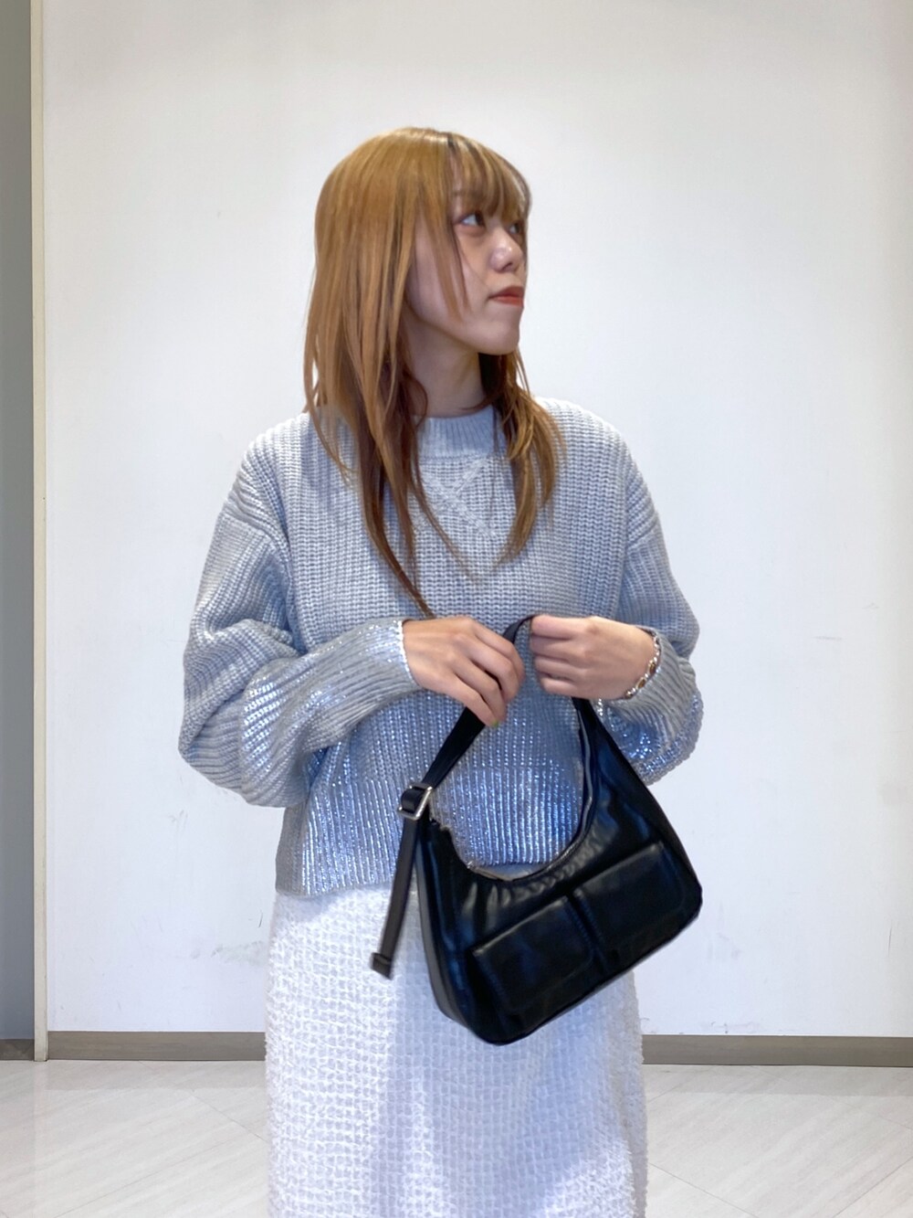 ホワイト系のスカート、ブラック系のショルダーバッグ、グレー系のニット/セーターを着用したレディースの冬コーディネートの3枚目の写真