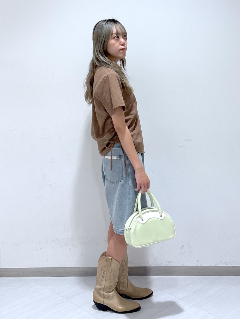 ブルー系のデニムパンツ、グリーン系のトートバッグ、ブラウン系のシャツ/ブラウスを着用したレディースの夏コーディネートの2枚目の写真