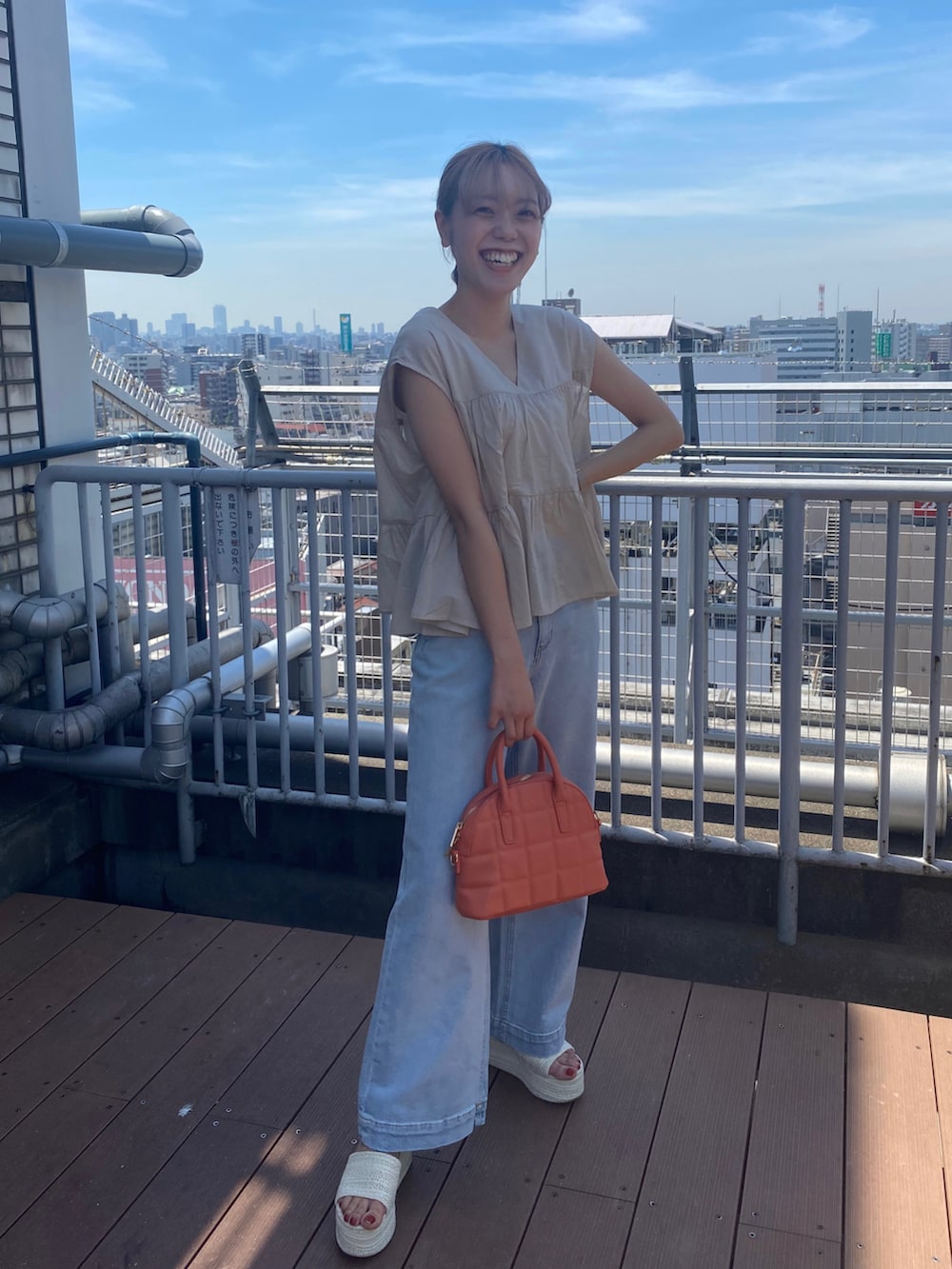 ホワイト系のサンダル、ブルー系のデニムパンツ、オレンジ系のハンドバッグを着用したレディースの夏コーディネートの2枚目の写真