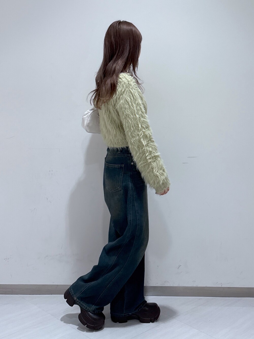ベージュ系のニット/セーター、ホワイト系のトートバッグ、ブルー系のデニムパンツを着用したレディースの冬コーディネートの5枚目の写真