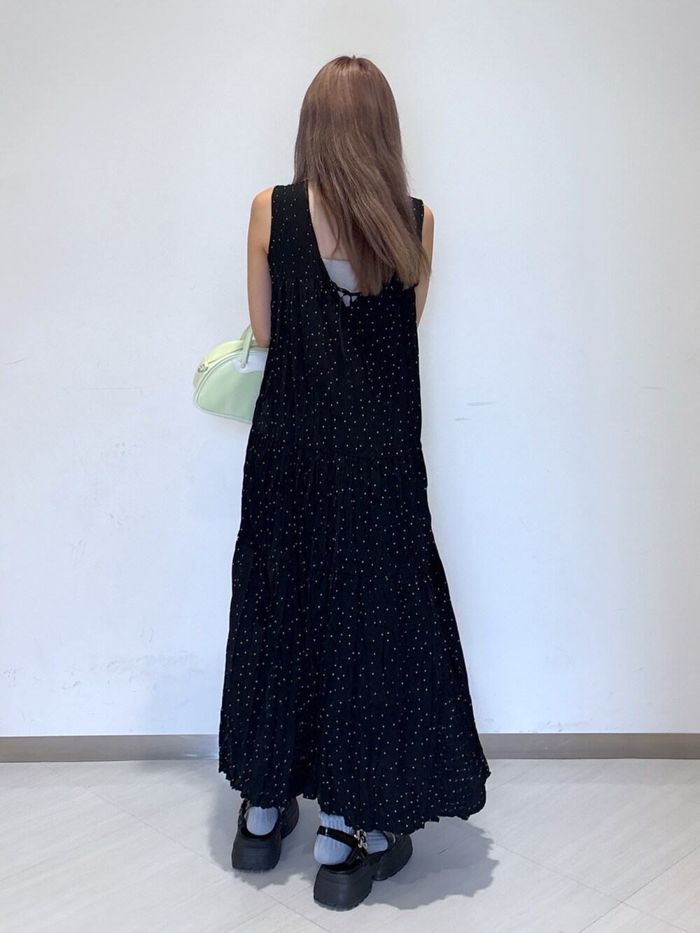 グリーン系のトートバッグ、ブラック系のワンピースを着用したレディースの夏コーディネートの3枚目の写真