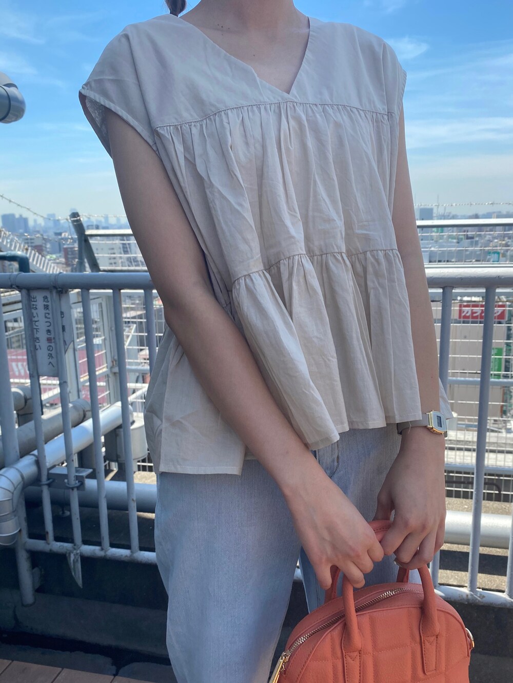 ホワイト系のサンダル、ブルー系のデニムパンツ、オレンジ系のハンドバッグを着用したレディースの夏コーディネートの5枚目の写真