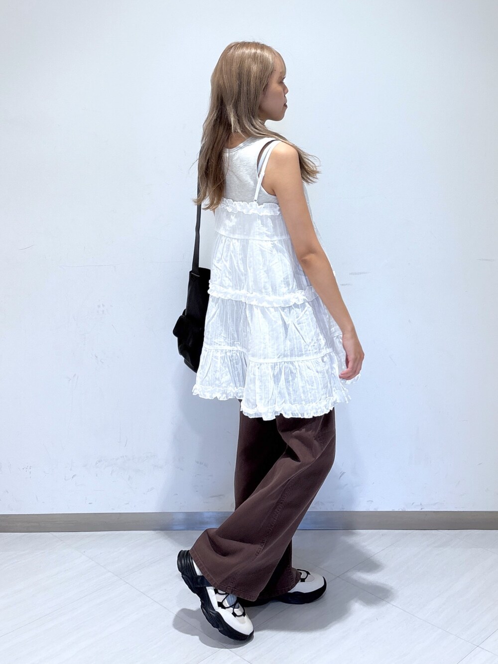 ブラウン系のデニムパンツ、ホワイト系のワンピース、ホワイト系のスニーカーを着用したレディースの夏コーディネートの4枚目の写真