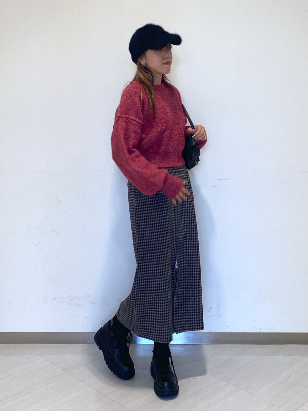 ブラック系のブーツ、ブラック系のハンドバッグ、ピンク系のニット/セーターを着用したレディースの秋コーディネートの2枚目の写真