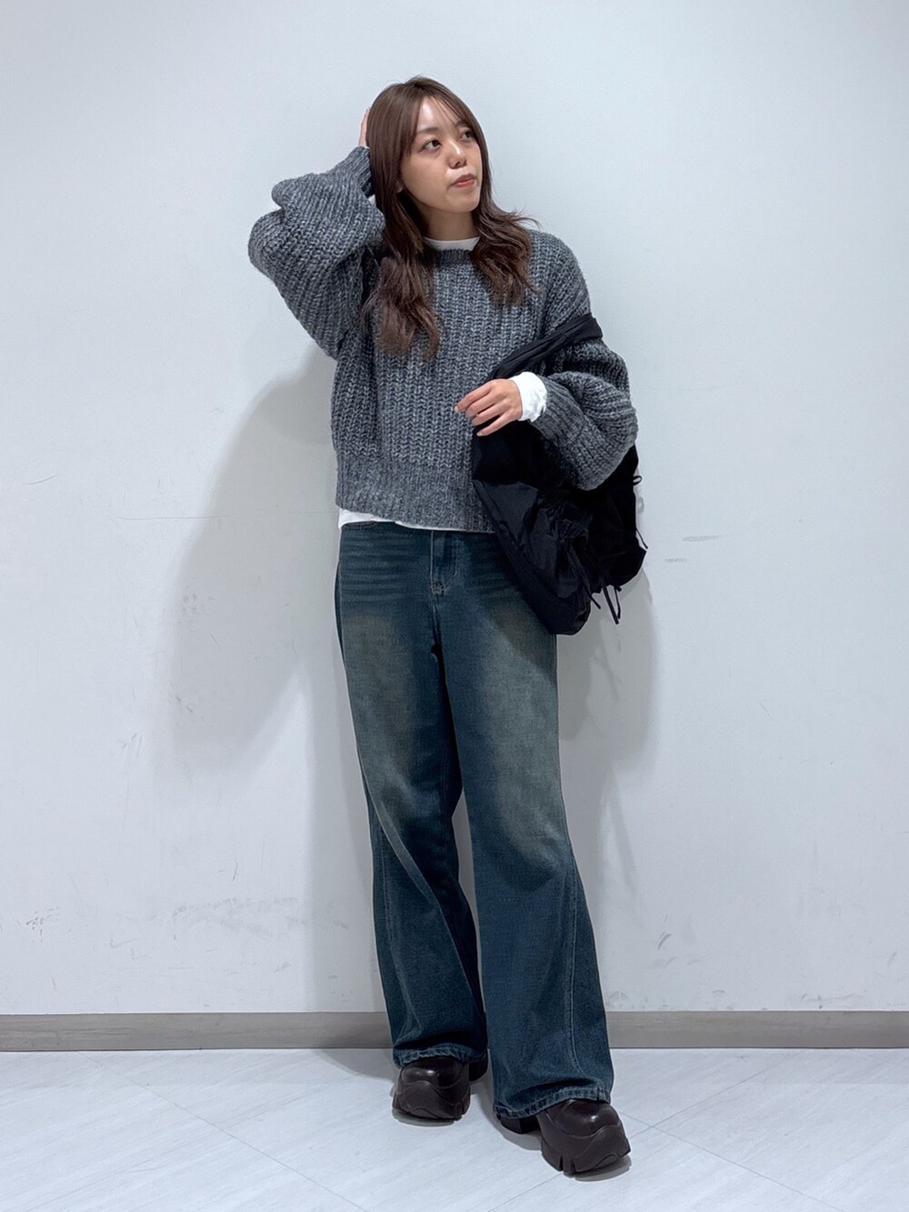ブラック系のトートバッグ、ブルー系のデニムパンツ、グレー系のニット/セーターを着用したレディースの冬コーディネートの2枚目の写真