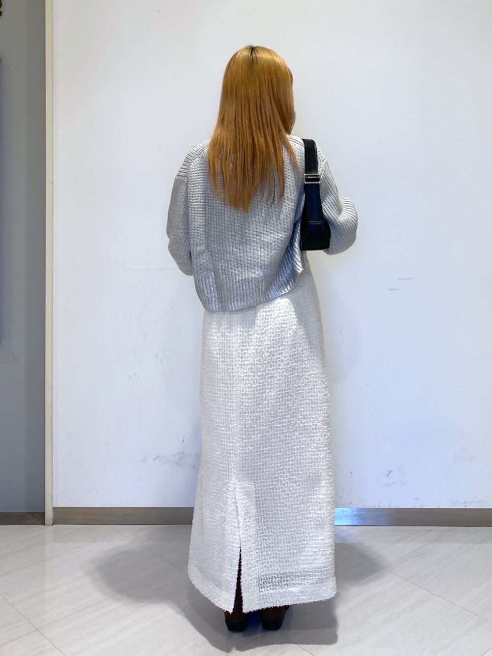 ホワイト系のスカート、ブラック系のショルダーバッグ、グレー系のニット/セーターを着用したレディースの冬コーディネートの2枚目の写真